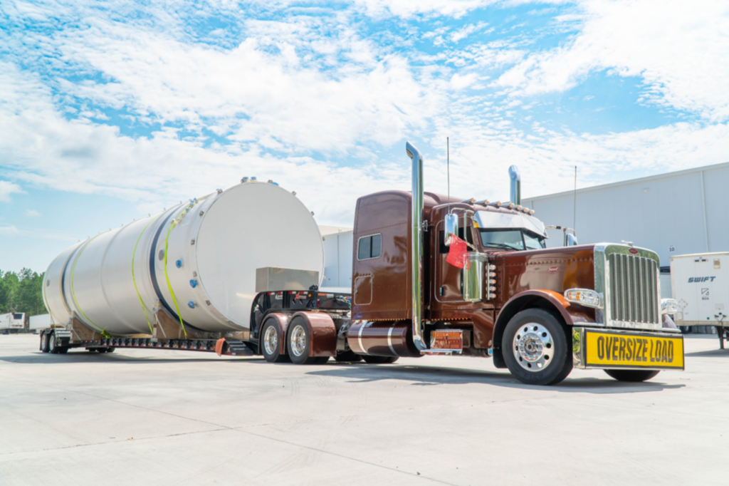 Heavy haul truck transporting a large industrial tank on a multi-axle trailer.