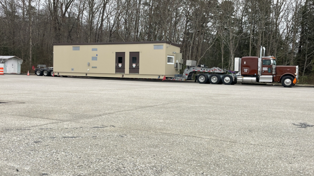 Heavy haul semi moving a skid-mounted modular unit building on a lowboy trailer.